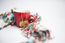 A red cup, a colorful scarf and gold earrings.