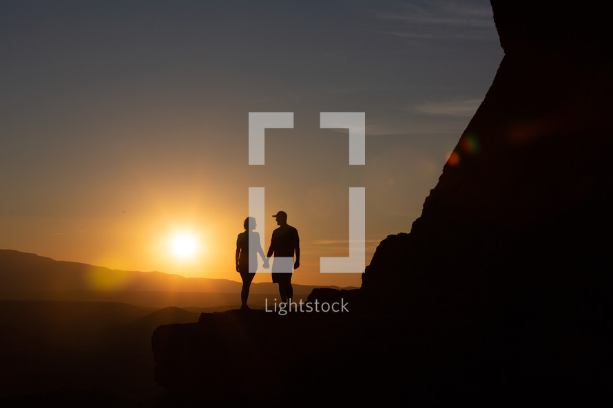 silhouette of a couple on a mountain at sunset 
