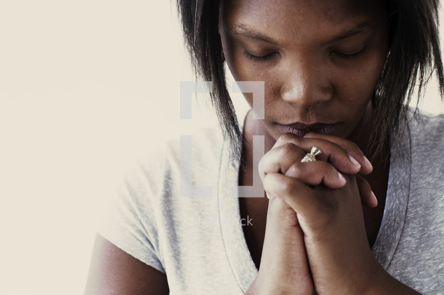 African-American woman with head bowed in prayer 
