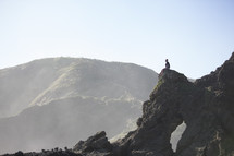 man sitting on a rock peak at the shore 