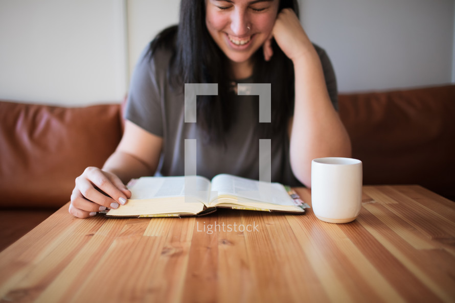 a young woman reading a Bible at a coffee shop 