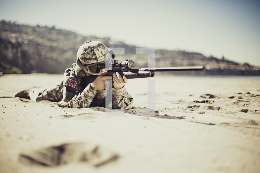 Military man shooting gun on a beach
