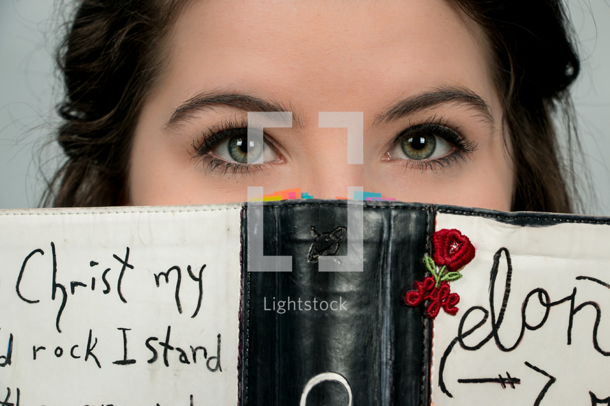 eyes of a teen girl looking over a book 