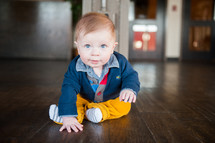 infant boy sitting on a wood floor 