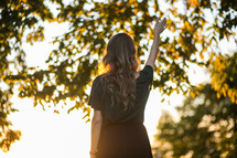 A woman standing outdoors with a  raised hand 