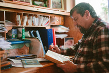 a man sitting at his desk reading a Bible 