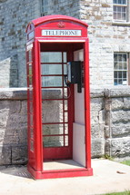 Telephone booth in front of a stone building.