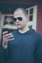 a man in sunglasses checking his cellphone 