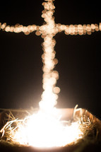 bokeh Christmas lights in the shape of a cross and a manger 