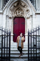 A woman posing in front of Cathedral doors in France 