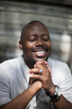 A smiling African American man with praying hands