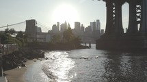 water lapping onto a shore and view of the Brooklyn bridge 