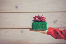 a woman holding out a wrapped Christmas present 