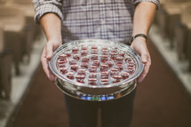 man holding a tray of communion cups