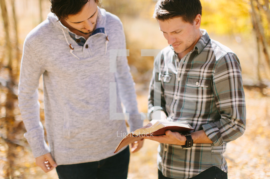 men reading and discussing scripture outdoors on a fall day 