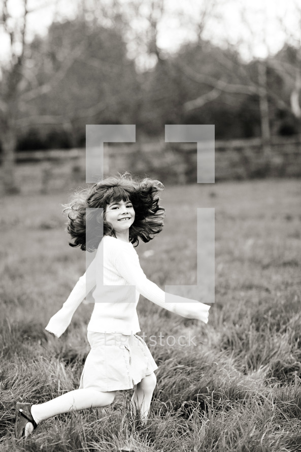 young girl running in grass field, dress, hair, smile.