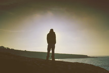 silhouette of a man looking out at water