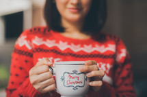 a woman holding a Merry Christmas coffee cup 