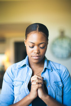 African-American woman with head bowed and praying hands 