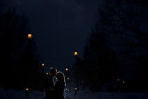 Silhouette of an embracing couple kissing in the snowfall.