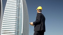 engineer with a hardhat standing in front of a high-rise building 
