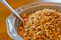 Spoon in a bowl of granola cereal.