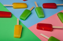 Brightly colored popsicles arranged on different colored papers.