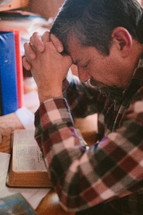a man sitting at his desk reading a Bible and praying 
