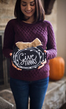a woman holding a give thanks plaque 