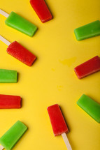 Red and green popsicles arranged on a yellow background.