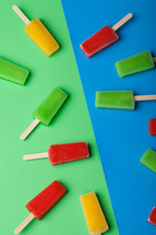 Brightly colored popsicles arranged on a blue and green background.