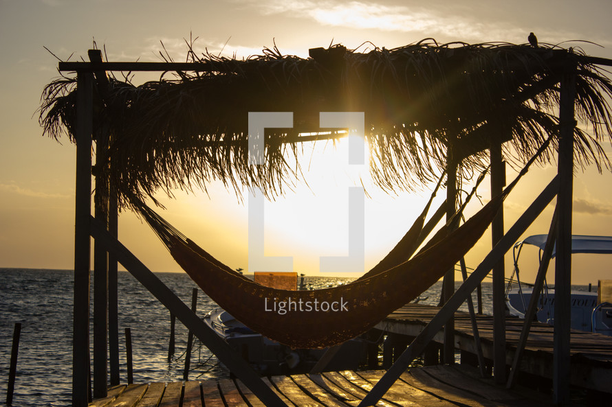 covered hammock on a dock at sunset 