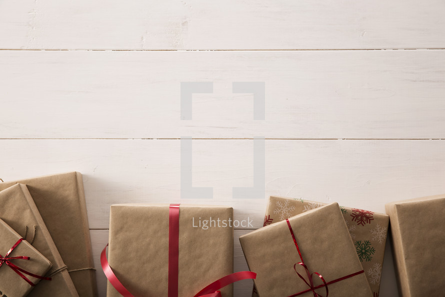 Gifts wrapped in brown paper and red ribbon on a white table.