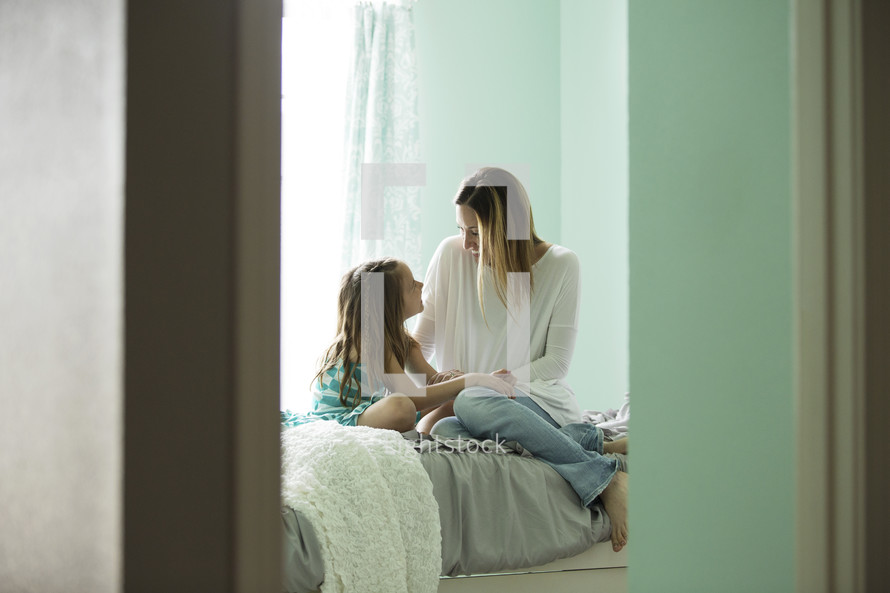 mother and daughter talking on a bed 