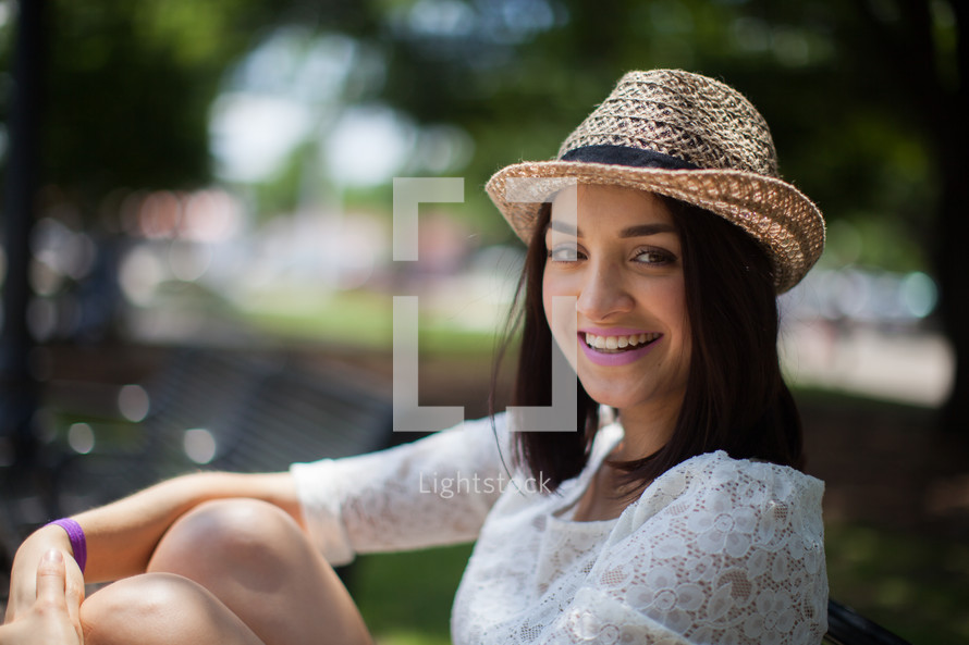 woman in a straw hat sitting outdoors 