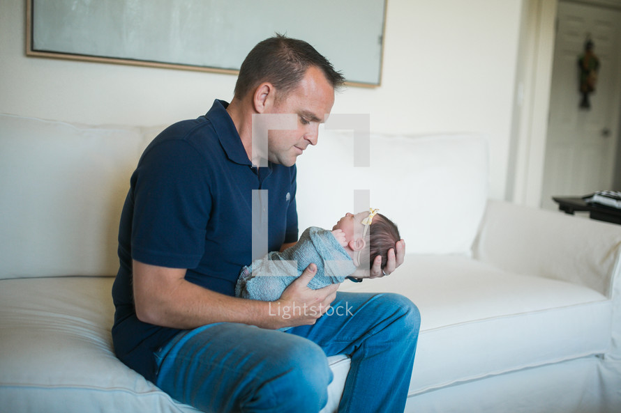 a father holding a swaddled newborn 