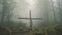 Paying under a wooden cross in the foggy