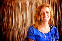 smiling face of a missionary woman near a straw hut 