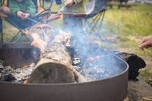 roasting hotdogs over a campfire 
