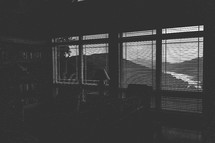 black and white window blinds and view of mountains and river 