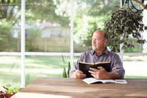 a man reading a Bible on a porch 