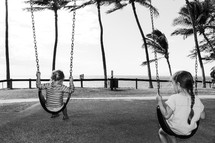 girls on a swing by a beach 