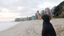 a woman filming the ocean with her cellphone 