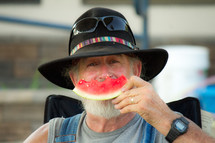 man in a hat eating watermelon 