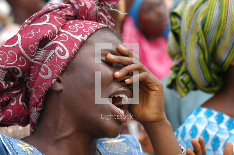 Woman praising God with hand over her face