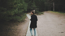 a woman walking along a wooden path 