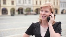 a young woman standing outdoors talking on a cellphone 