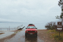 a red jeep cherokee parked by a boat ramp 