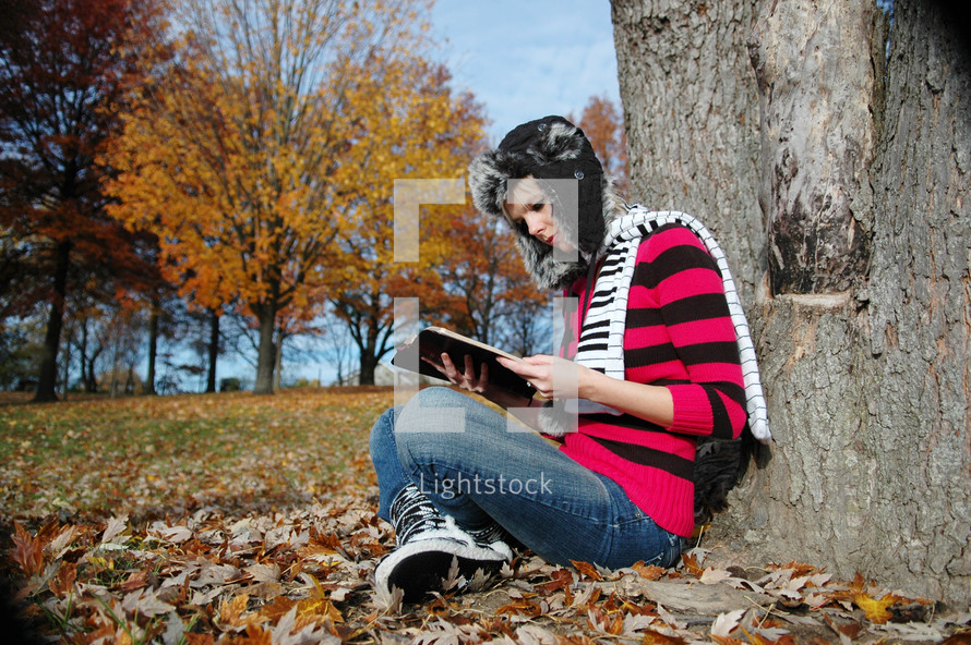 teen girl reading under a tree 