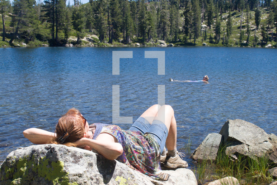 woman sleeping on a rock by a lake 